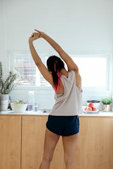 A woman performs a morning stretch in a bright, modern kitchen setting, promoting wellness.