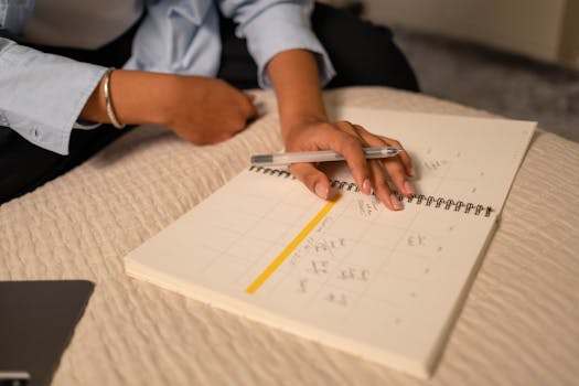 Close-up of a person scheduling in a spiral-bound planner using a pen. Indoor setting.