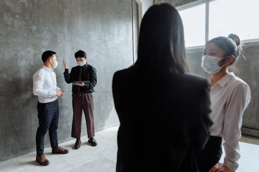 Group of professionals wearing masks, discussing business indoors, adapting to new normal.